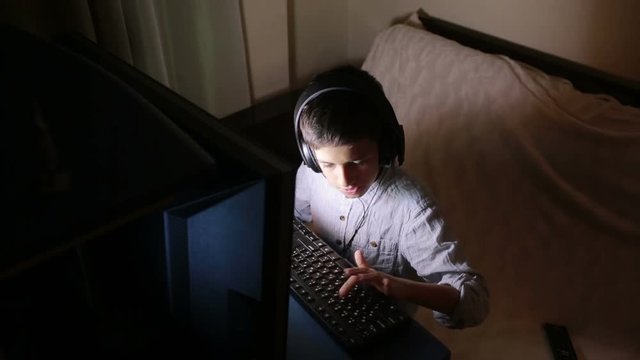 Teen boy plays games on the computer at night. Online Games