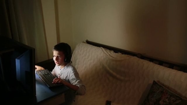 Teen boy plays games on the computer at night. Online Games