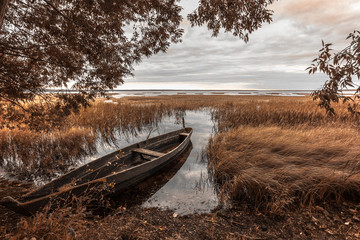 the old wooden boat on the yellow autumn coast of the lake