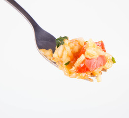 Risotto with chicken, tomatoes, bell pepper, onion, garlic and parsley on a fork on a white background 