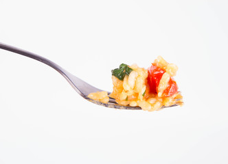 Risotto with chicken, tomatoes, bell pepper, onion, garlic and parsley on a fork on a white background 