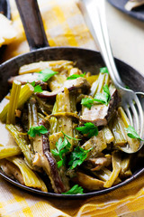 stewed celery with cepes in a vintage frying pan.