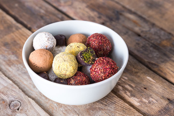 Colorful dessert, raw vegan sweets and organic chocolate in a bowl on a wooden background. 