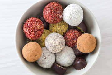 Colorful dessert, raw vegan sweets and organic chocolate in a bowl, top view. 
