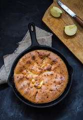 Homemade apple pie in vintage iron pan on dark background.