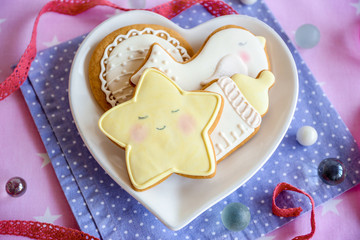 Baby glazed cookies in heart shape plate on decorated table