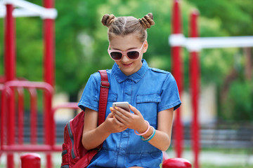 Cute young girl with phone in park