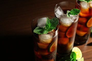 Cuba Libre cocktails with lime and mint on dark background