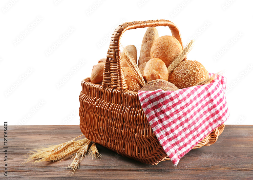 Wall mural Wicker basket with fresh bread on wooden table