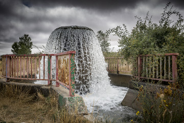 Water gushes from pipe to feed an irrigation watercourse canal