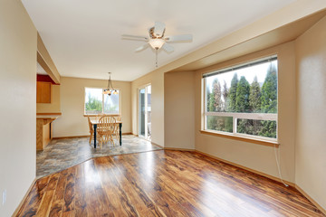 Empty hallway interior with hardwood floor, connected to dining area with tile floor.