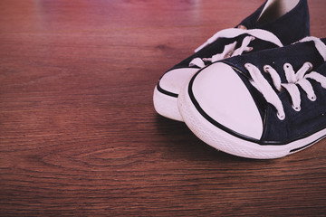 Old canvas shoes on a wooden floor Vintage Retro Filter.
