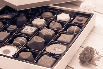 Chocolate candy in the box on wood background.