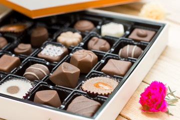 Chocolate candy in the box on wood background.