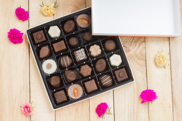 Chocolate candy in the box on wood background.