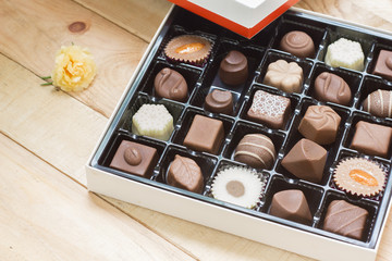 Chocolate candy in the box on wood background.