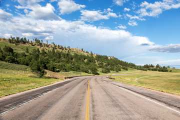 Fototapeta na wymiar A road cuts through the hills of eastern Wyoming on a summer day. 