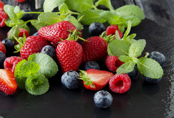 fresh strawberries, raspberries and blueberries on a black background
