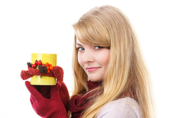 Smiling girl in woolen gloves holding decorated cup of tea, autumn decoration