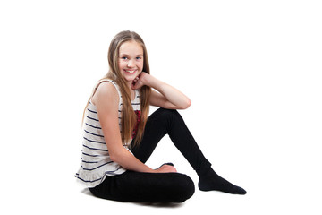 Fototapeta premium A smiling girl is sitting on floor, isolated on white background