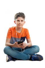 A schoolboy is listening music on mobile phone, isolated on white background