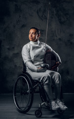 Female fencer in wheelchair with safety mask and rapier.