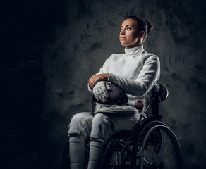 Female fencer in wheelchair with safety mask and rapier.