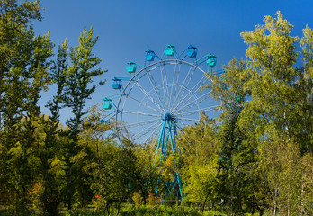 Ferris wheel in Siberia, autumn panoramic view, park area with beautiful trees.