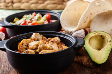 Ingredients ready for preparing chicken tacos with salsa made from avocado, tomatoes, and chilli peppers