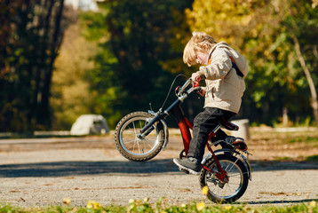 Little boy doing a wheelie on rear wheel