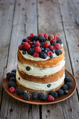 Tasty cake with strawberry, raspberry and blackberry on a wooden table