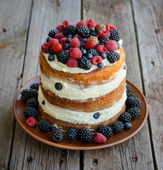 Tasty cake with strawberry, raspberry and blackberry on a wooden table