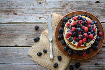 Tasty cake with strawberry, raspberry and blackberry on a wooden table