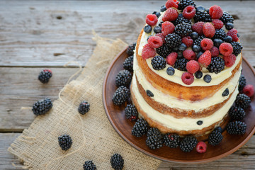 Tasty cake with strawberry, raspberry and blackberry on a wooden table