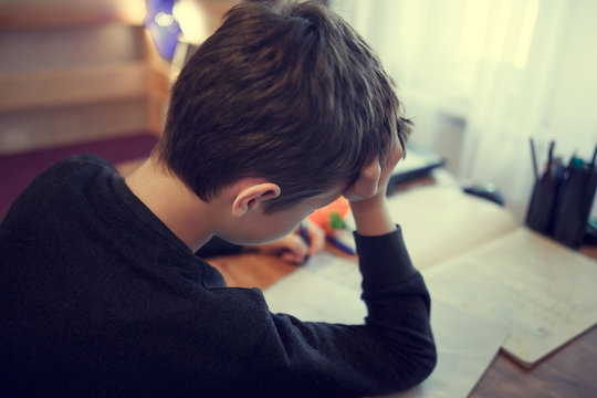 Sad schoolboy doing homework