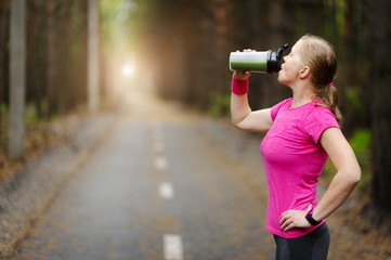 Sporty woman drinking detox green smoothie in the Park.