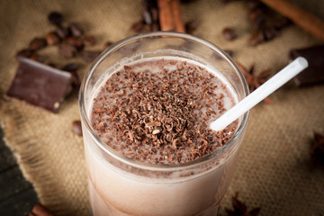 Photo of fresh Made Chocolate Banana Smoothie on a wooden table with coffee and spices. Selective focus. Milkshake. Protein diet. Healthy food concept. Drink, coffee beans, chocolate, 