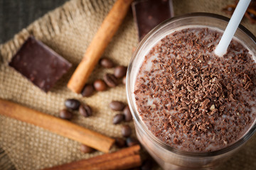 Photo of fresh Made Chocolate Banana Smoothie on a wooden table with coffee and spices. Selective focus. Milkshake. Protein diet. Healthy food concept. Drink, coffee beans, chocolate, 