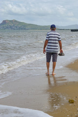 Healthy senior man walking on Pallarenda beach, Townsville with city in the background