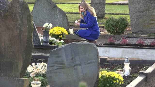 Young woman lights candle lantern in memory of husband father in cemetery. 4K