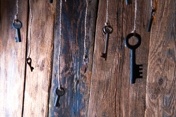 Many keys hanging on a string. Wooden background. Selective focus