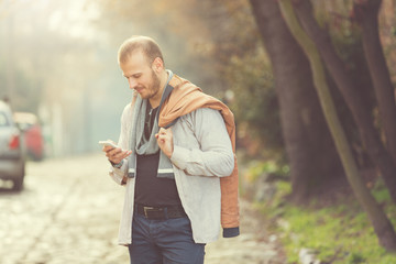 Modern man using smartphone outdoors.

