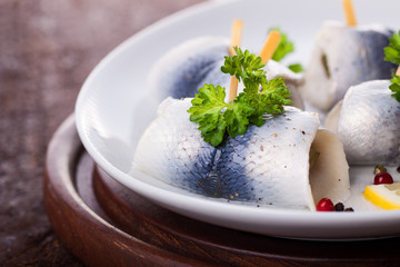 Rollmops (rolled marinated herring) with marinated cucumber, salt, pepper and parsley, closeup
