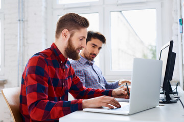 Two web designers working in office on laptop