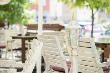 Outdoor cafe interior. Selective focus on lantern. Blurred bright background.