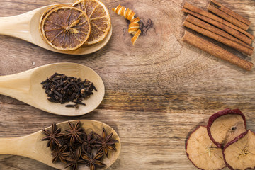 star anise, cloves and dried orange on wooden spoon with cinnamon and dried apple