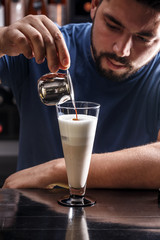 Barista is pouring coffee in milk