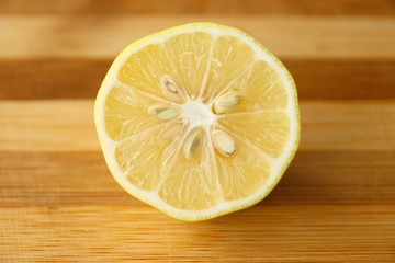 Slice of lemon fruit with seeds on wooden board
