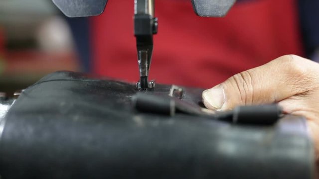 Calzolaio al Lavoro nella sua bottega artigianale. Cucitura fondina nera per pistola. 