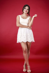 Young beautiful female model in white dress on red background